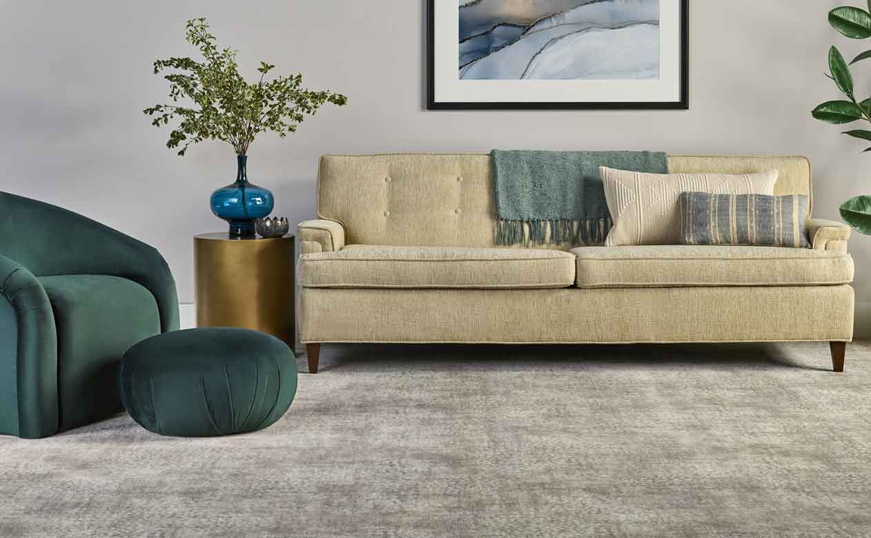Tan plush carpet in living area with tan midcentury modern couch and green furniture